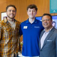 Three gentlemen standing together at event and smiling for photo
